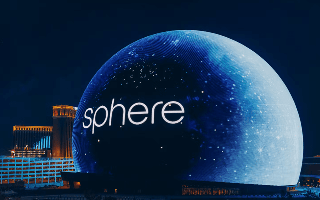 The Sphere lit up blue with a starry display at night in Las Vegas, sphere wordmark glowing