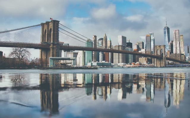 Brooklyn Bridge and Lower Manhattan skyline reflected in calm water, New York City