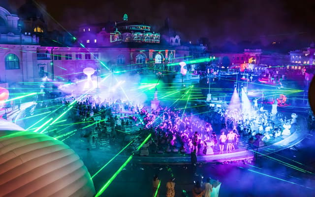 Night Sparty at Szechenyi thermal baths in Budapest with green and purple laser lights over the pools
