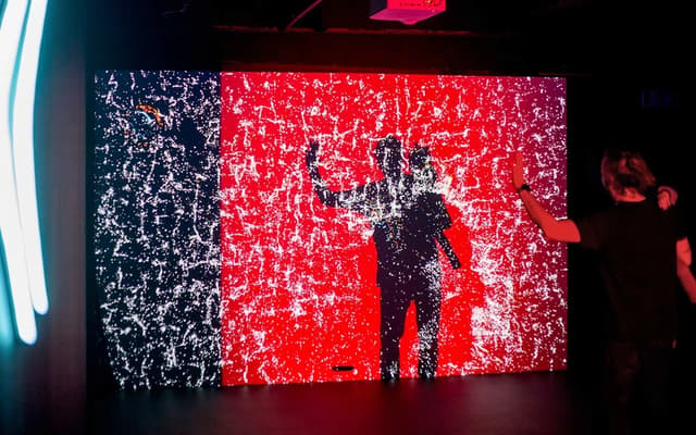 Visitor before a glowing red and black illusion art light wall at a themed museum in Prague