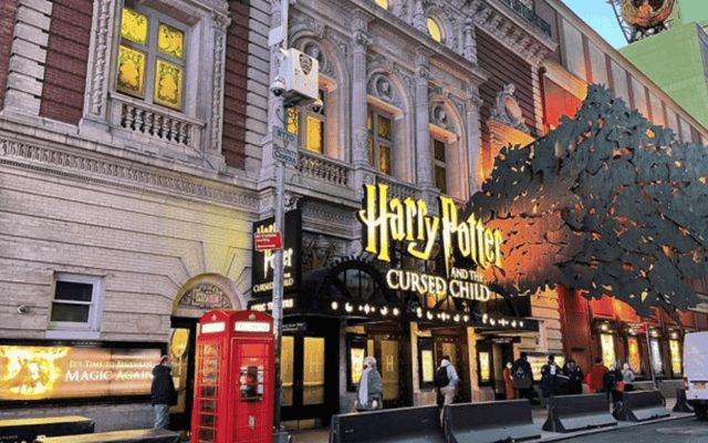 Theatre facade with the Harry Potter and the Cursed Child marquee and a red phone box outside