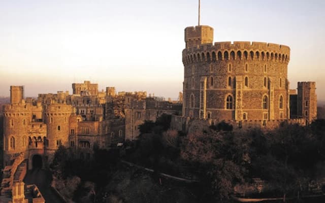 Windsor Castle and its Round Tower glowing at golden hour above the town