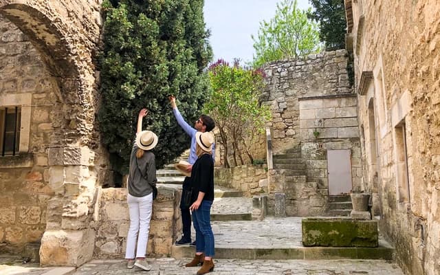 Two visitors in sun hats exploring old stone houses and steps in a Provence village