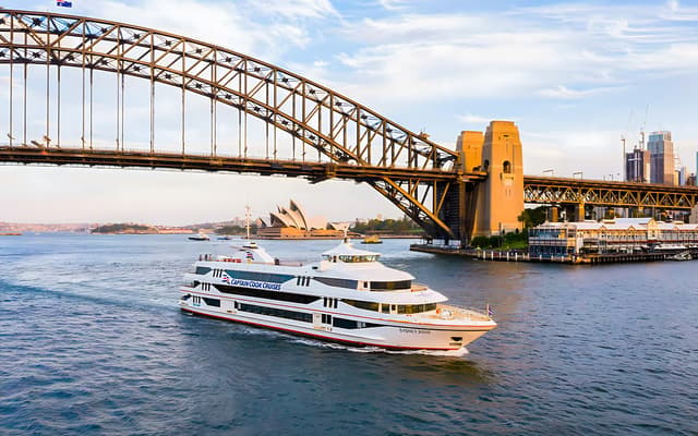 Captain Cook Cruises dining boat passing under Sydney Harbour Bridge with the Opera House behind