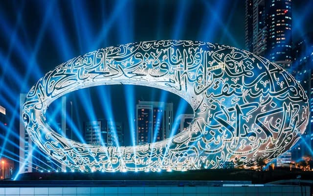 Dubai Museum of the Future ring lit at night with blue searchlights and the skyline behind