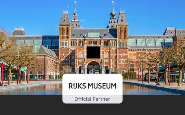 The red-brick Rijksmuseum in Amsterdam reflected in its garden pool under a blue sky