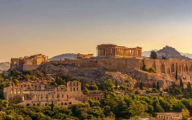 The Acropolis and Parthenon glowing at sunset above the city of Athens