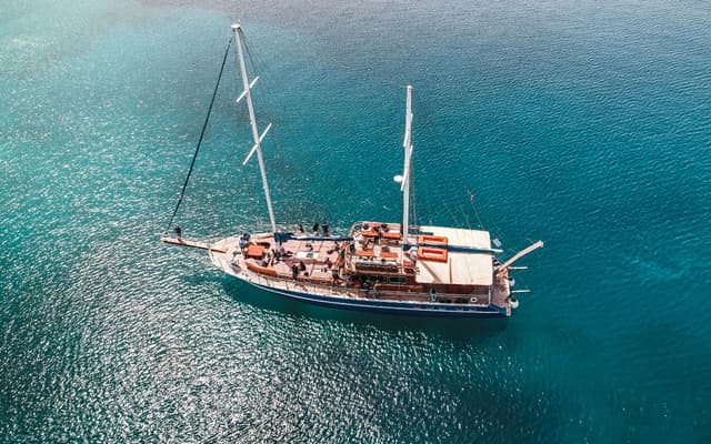 Aerial view of a wooden sailing boat on the turquoise Aegean sea on a Greek island cruise near Athens