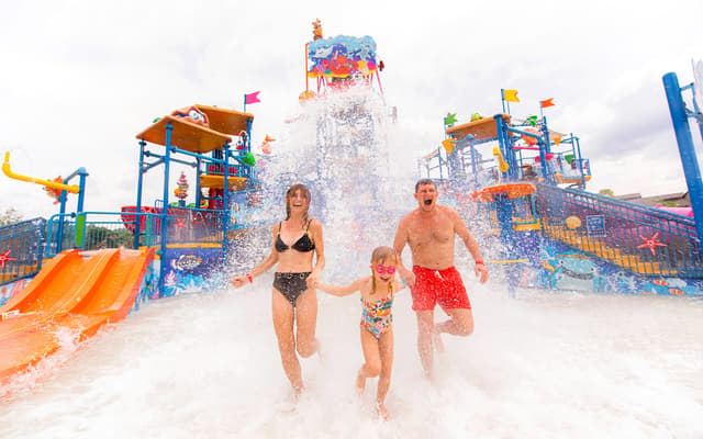 Family running through splashing water at a colourful family water park in Phuket