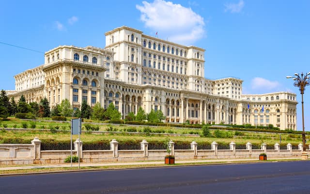 The Palace of the Parliament in Bucharest, a vast white neoclassical government building under blue sky