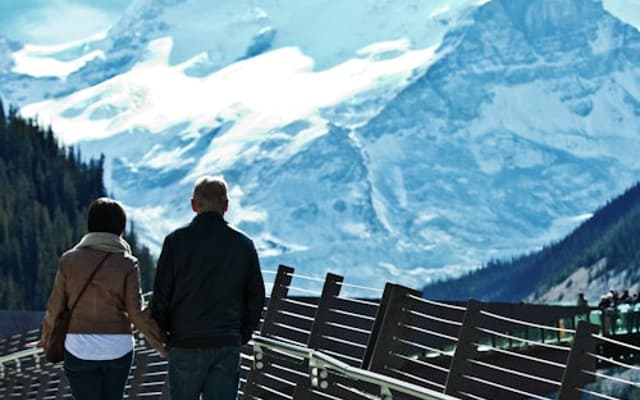 A couple walk along the scenic skywalk overlooking the mountains.