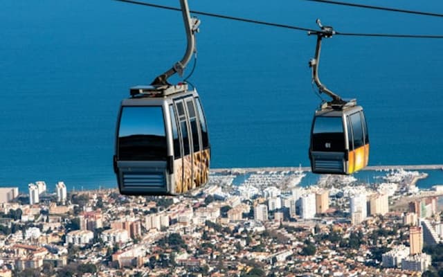 Cable car cabins climbing above the coastal town and sea at Benalmadena