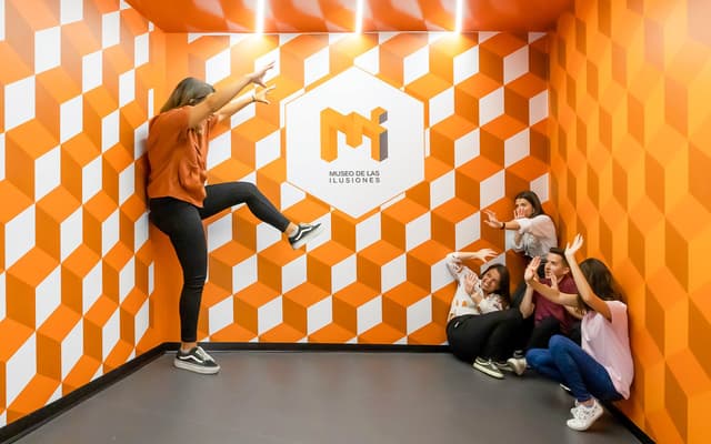 People posing in an orange geometric optical illusion room at Seville's Museum of Illusions