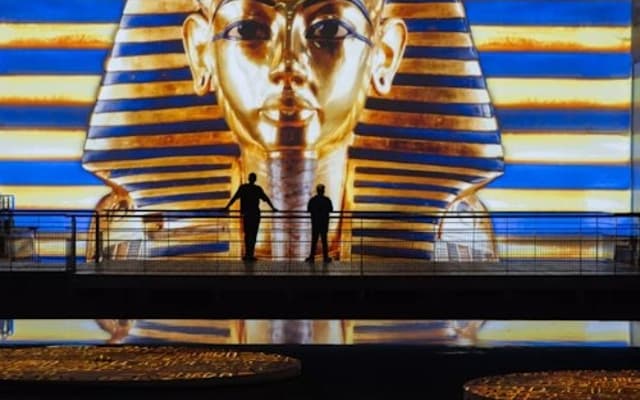 Giant golden Tutankhamun projection at a Bordeaux immersive digital art show with visitors