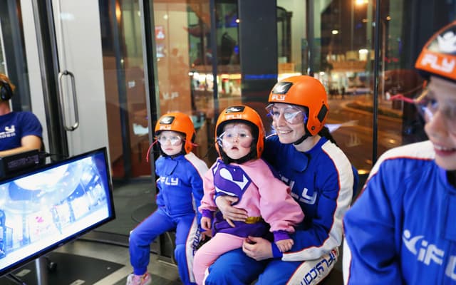 Family in blue iFLY jumpsuits and orange helmets ready for indoor skydiving on the Gold Coast
