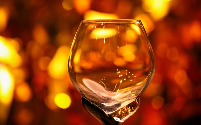 Empty whisky tasting glass glowing against warm golden bokeh lights in Edinburgh