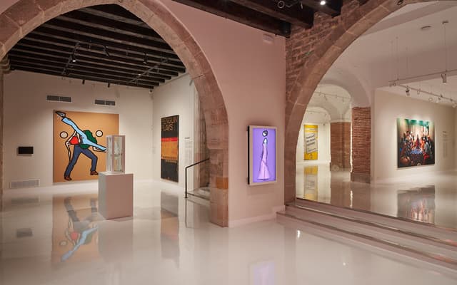 Contemporary art gallery in Barcelona with stone arches and bold modern paintings