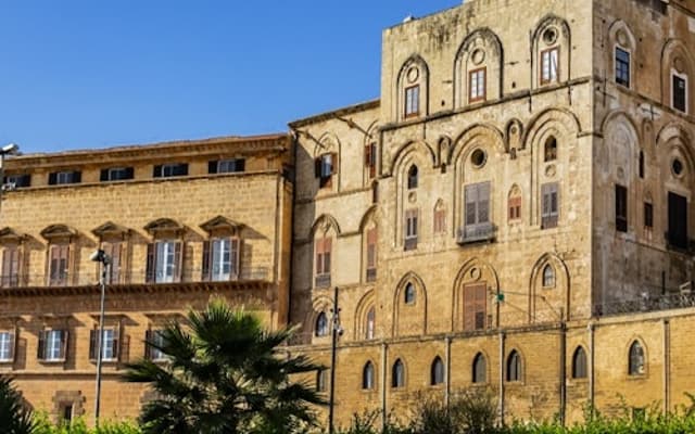 The honey-stone Norman Palace in Palermo, a historic Sicilian royal residence above green gardens