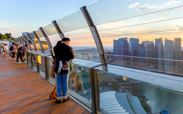 Couple at the Marina Bay Sands SkyPark observation deck overlooking the Singapore skyline at sunset