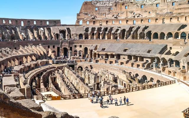 Interior of the Roman Colosseum in Rome with tiered ruins and visitors on the arena floor