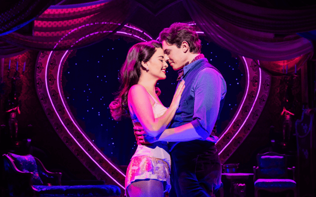 Broadway musical scene with a couple embracing beneath a glowing pink neon heart and starry backdrop