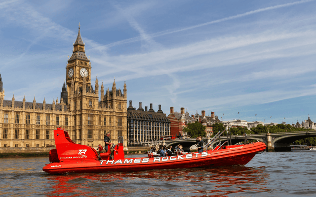 Red Thames Rockets speedboat passing Big Ben and the Houses of Parliament on the River Thames in London
