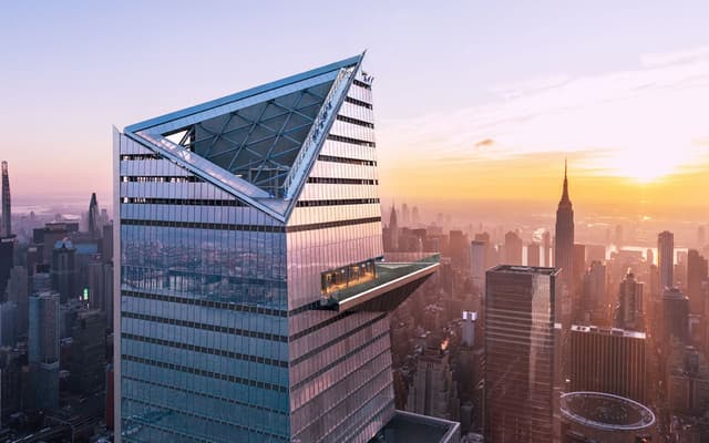 Edge observation deck glass platform jutting over the New York City skyline at sunset