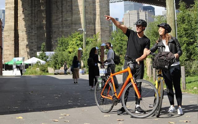 Cycling across the Brooklyn Bridge with the Manhattan skyline behind