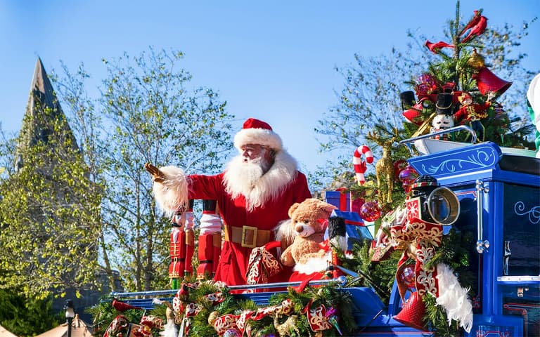 Santa Claus waving from a decorated float in a Christmas parade at Magic Kingdom