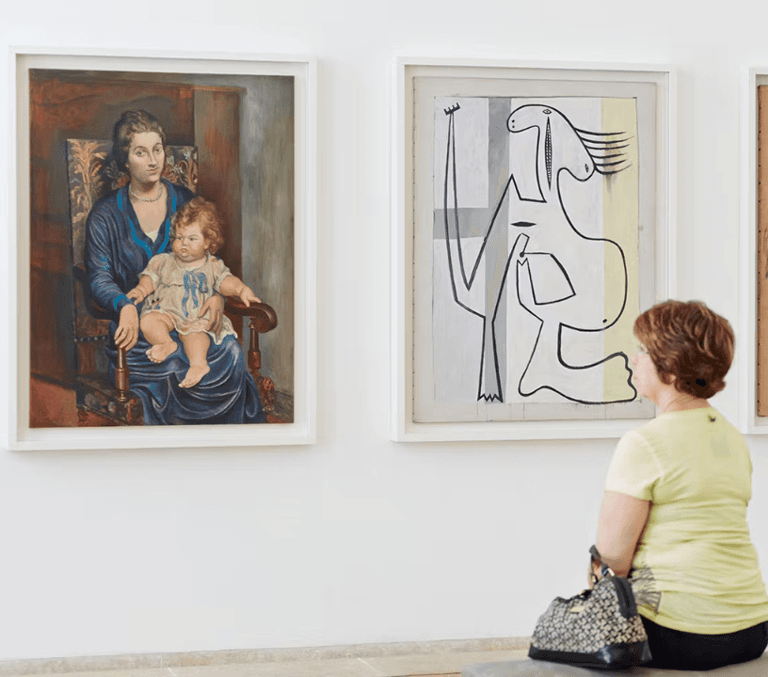 Visitor seated viewing modern paintings in a Paris art gallery