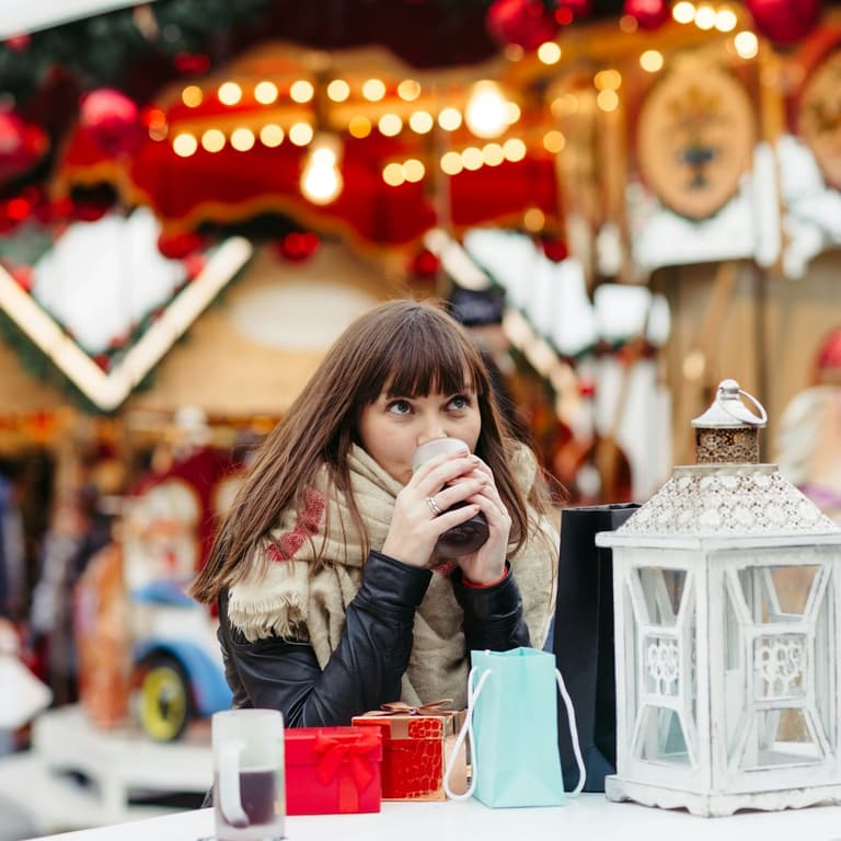 A visitor holding a warm drink at a Christmas market stall in Vienna