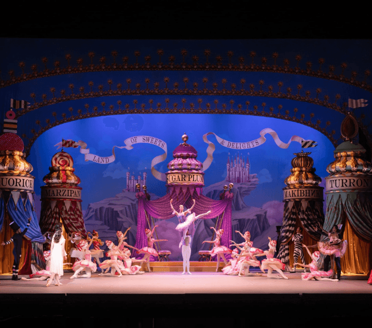 ENB's Nutcracker tickets. A wide view of the stage, a ballerina is in a lift centre stage.