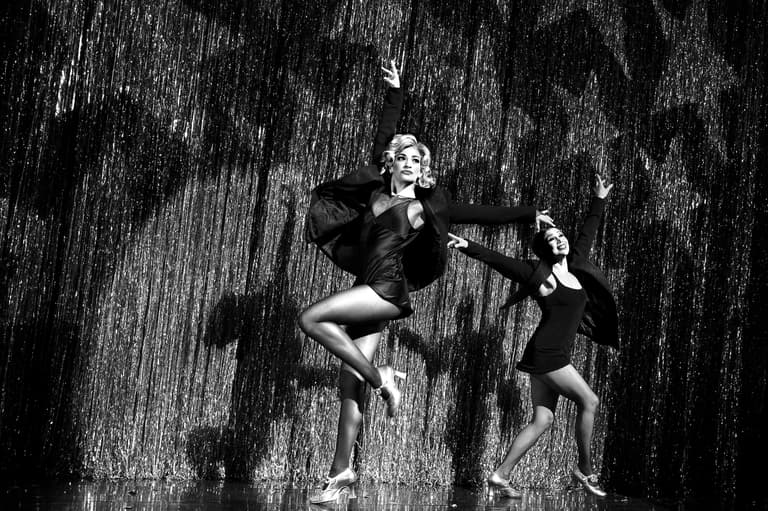 Two performers dancing in front of the silver fringe curtain in Chicago at the Ambassador Theatre on Broadway