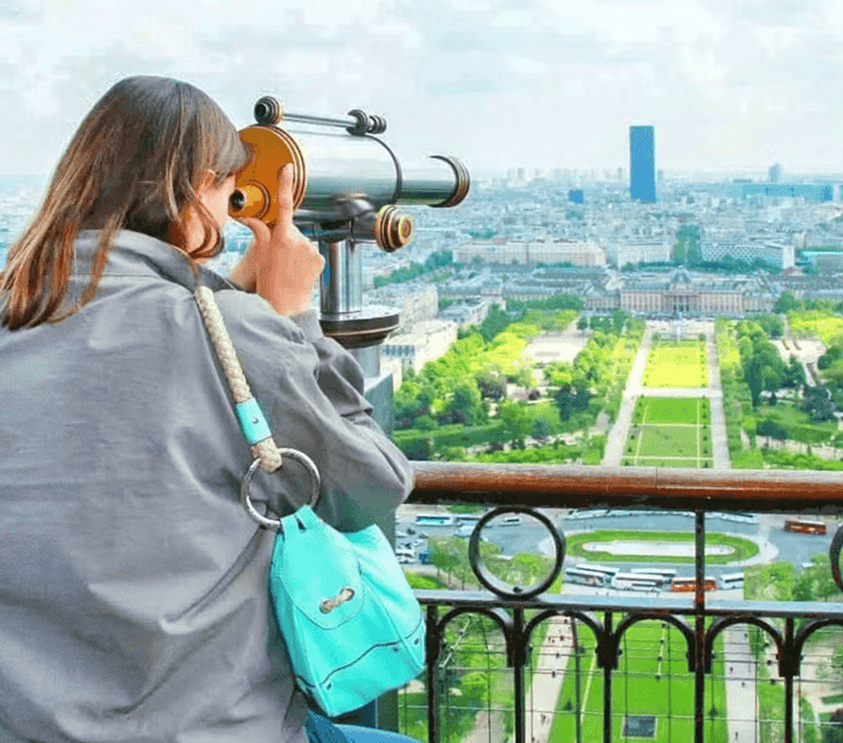 Visitor at Eiffel Tower telescope overlooking the Champ de Mars in Paris