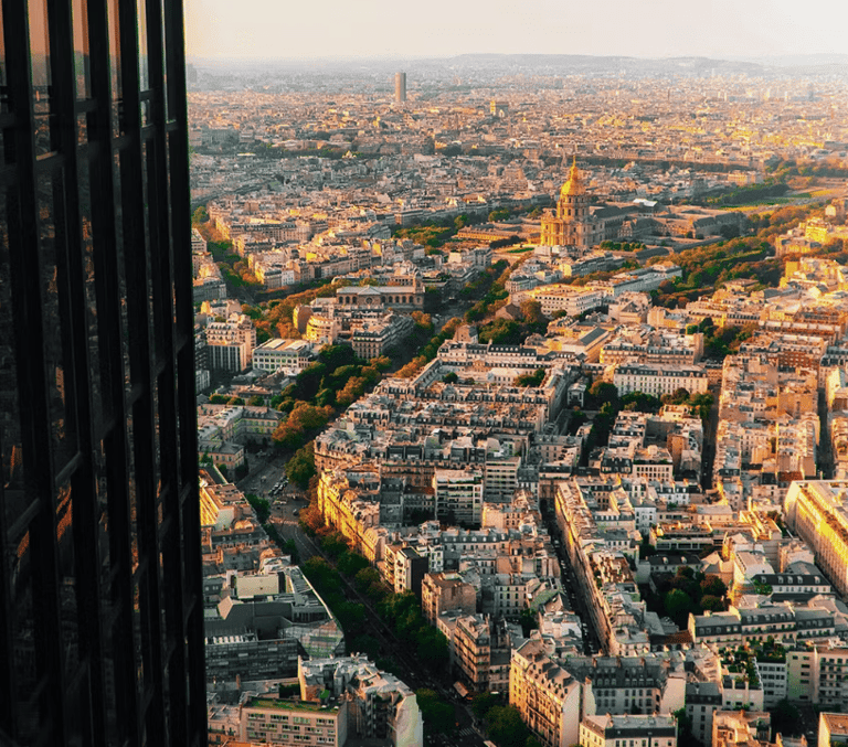 Golden-hour aerial view over Paris rooftops with the Eiffel Tower in the distance