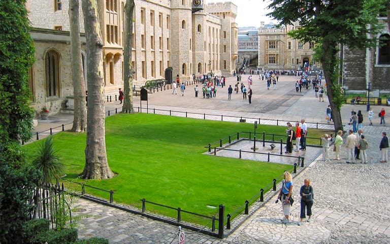 A Yeoman Warder in traditional uniform speaking with visitors at the Tower of London