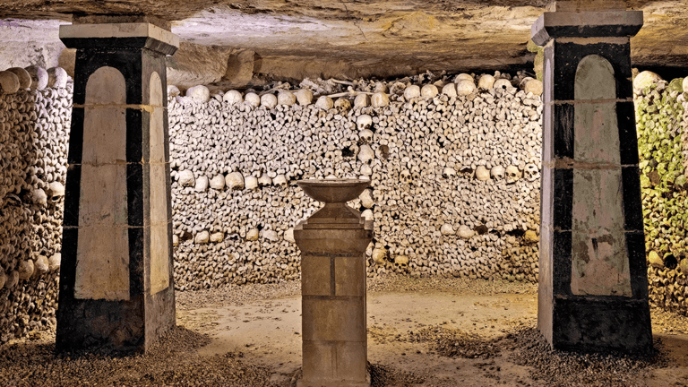 Υπόγειος διάδρομος των Paris Catacombs με προσεκτικά τακτοποιημένα οστά του οστεοφυλακίου της πόλης