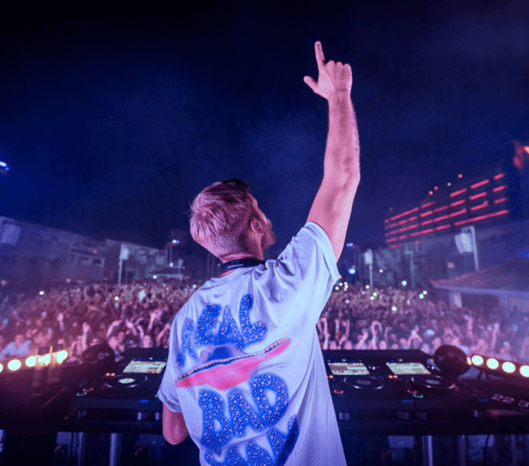 DJ raising hands to a packed open-air crowd at night at Ushuaia Ibiza