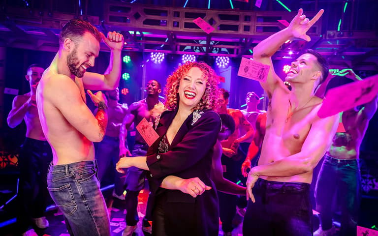 Seorang ahli penonton dibawa ke pentas semasa Magic Mike Live, menari bersama dua orang penghibur