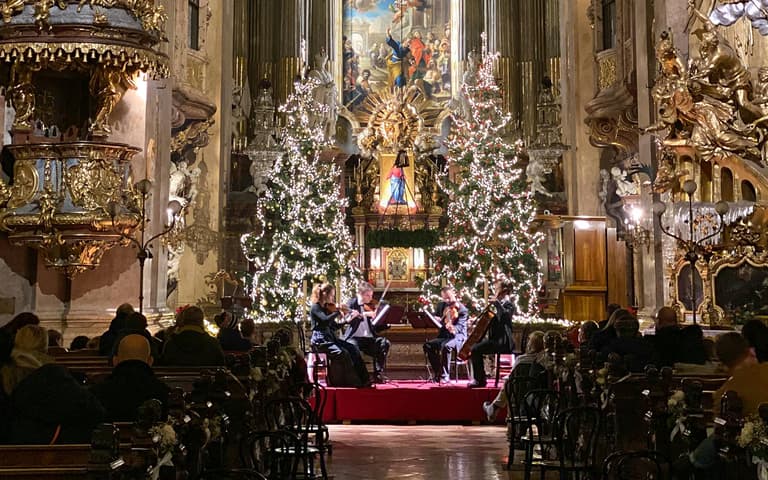 A chamber ensemble playing beside a Christmas tree inside St Peter's Church in Vienna