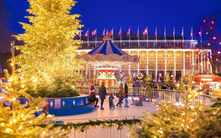 A giant illuminated Christmas tree and carousel at Tivoli Gardens in Copenhagen