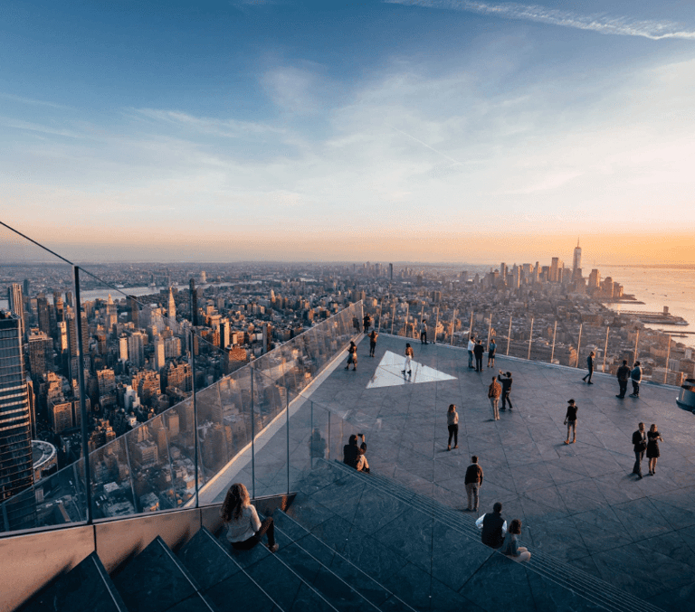 Visitors on the Edge glass-floor observation deck overlooking Manhattan at sunset