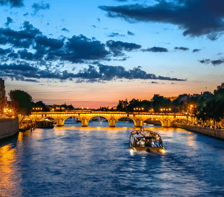 Seine river cruise boat passing under a bridge at sunset in Paris