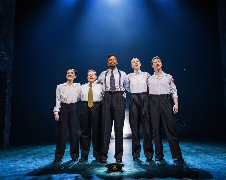 The cast of Operation Mincemeat standing together on stage at the Golden Theatre