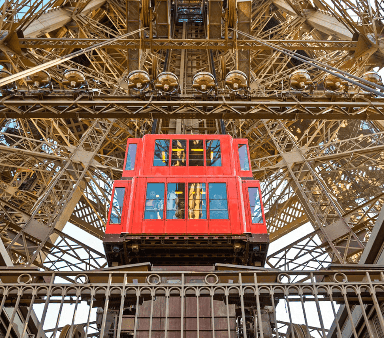 Red Eiffel Tower elevator car climbing through the iron lattice in Paris