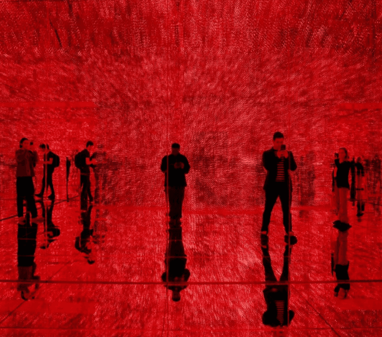 Silhouettes of visitors inside a glowing red immersive light art installation
