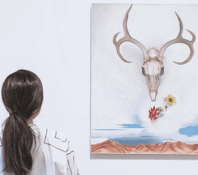 Visitor viewing a Georgia O'Keeffe cow skull painting in a New York art gallery