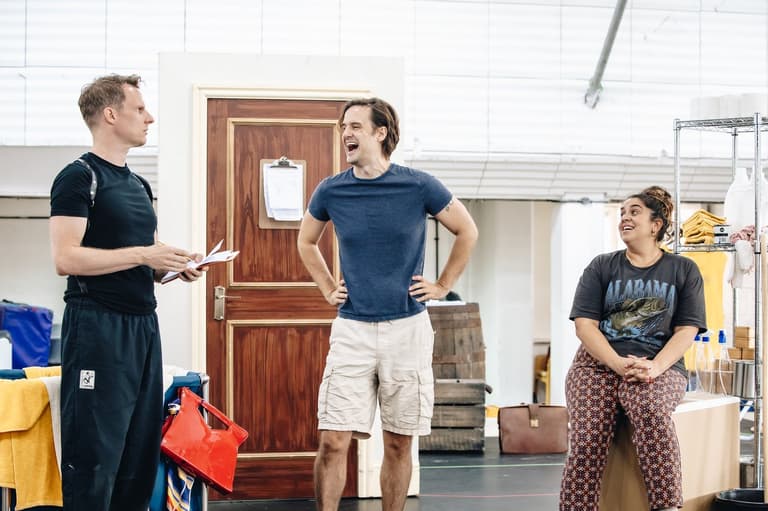 Three cast members share a laugh mid-scene in rehearsal for The Comedy About Spies