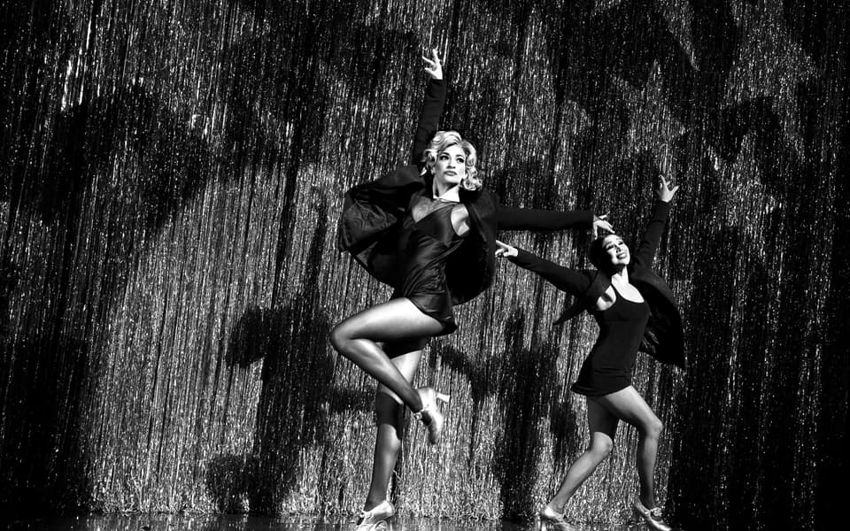 Two performers dancing in front of the silver fringe curtain in Chicago at the Ambassador Theatre on Broadway