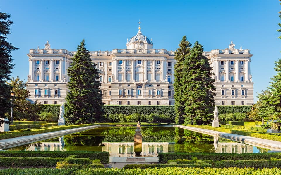 The Royal Palace of Madrid behind the formal Sabatini Gardens under a clear blue sky